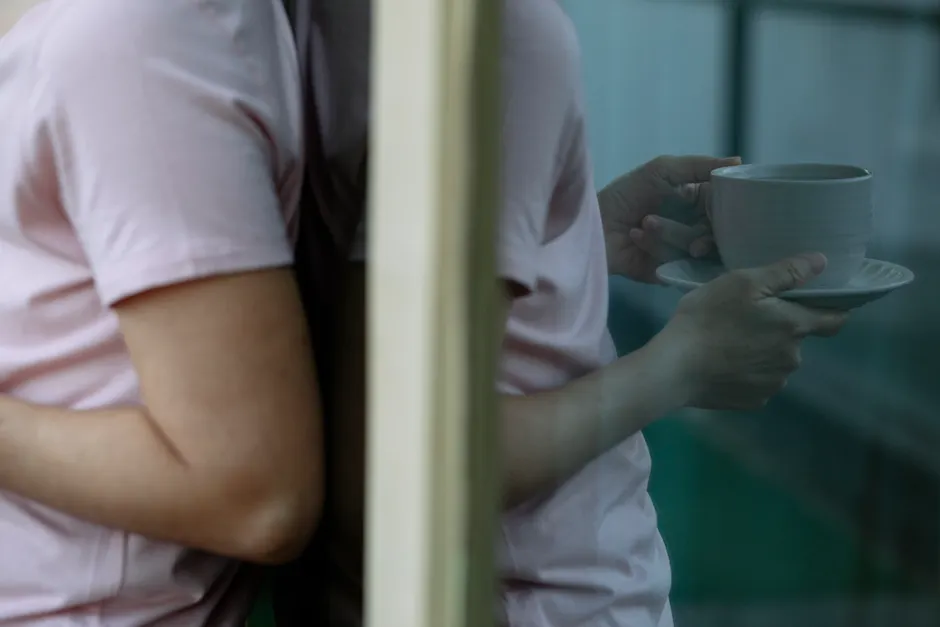 Anosognosie : pourquoi une personne peut ignorer un trouble réel Side view of crop unrecognizable person in pink t shirt leaning on glass door and drinking cup of coffee on terrace