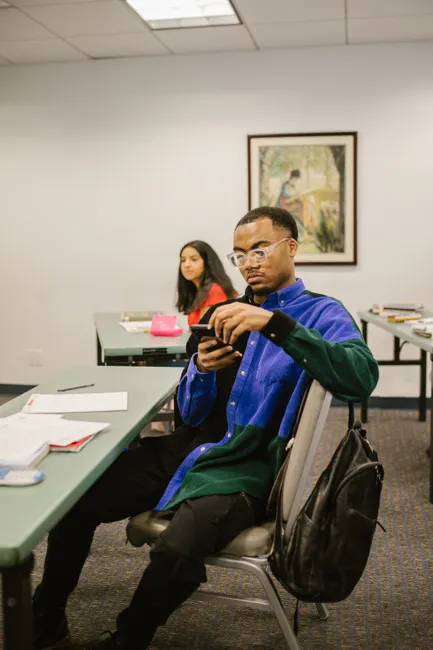 Students in a classroom setting using smartphones, engaging in study activities.