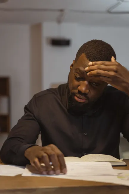 Thoughtful man reading and concentrating on notes at a desk indoors.