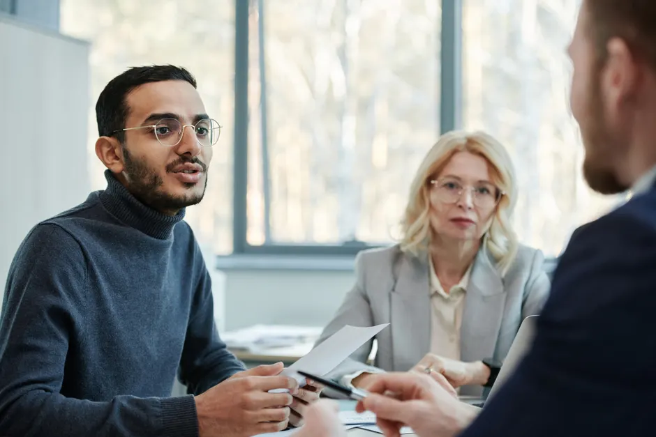 Three diverse colleagues engaging in a business discussion in a modern office setting.