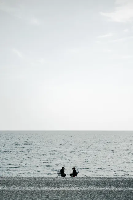 Two people relaxing on a serene beach, capturing peaceful solitude by the sea.