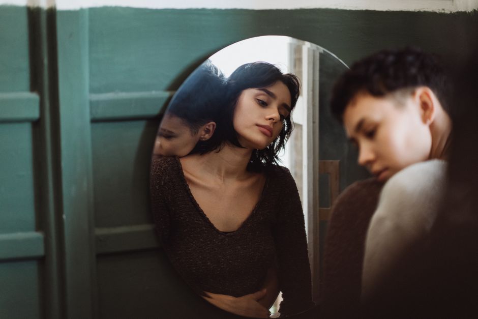 La honte en santé mentale : quand elle isole et retarde la demande d’aide Two people sharing a reflective moment, captured through a mirror in an intimate setting.