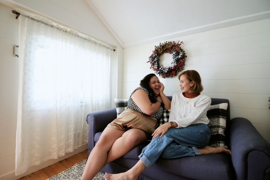 Two women enjoying a friendly conversation on a sofa in a cozy, bright living room.