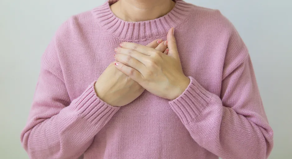 Auto-compassion après un traumatisme : ce que montrent les études sur la croissance post-traumatique Unrecognizable female wearing pink sweater standing on white background with crossed hands on chest in light room in daytime inside