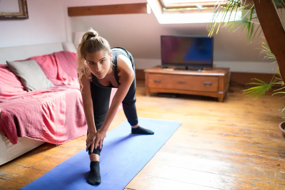 Woman exercising indoors on a yoga mat, stretching and staying fit at home.