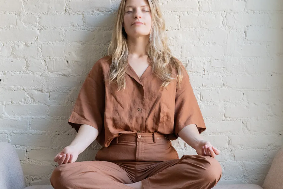 Woman meditating indoors, practicing mindfulness and relaxation in a calm setting.