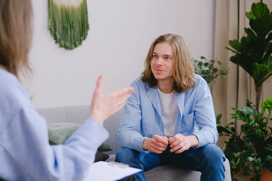 Traitement du trouble borderline : ce que montrent les études de 2024 et 2025 Young man with long hair in a therapy session, actively engaged in conversation.