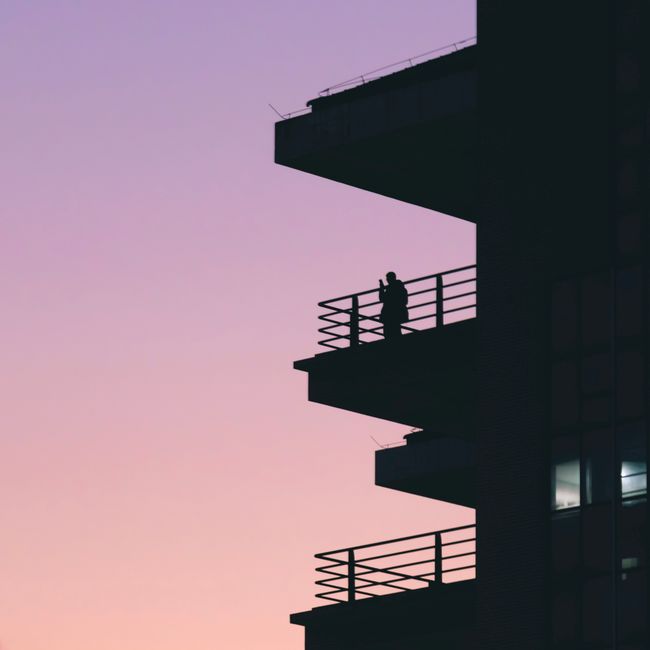 A captivating silhouette of a person on a balcony against a twilight sky.