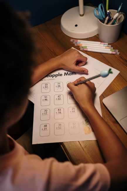 A child focuses on solving a math worksheet at a home study desk, fostering learning and concentration.