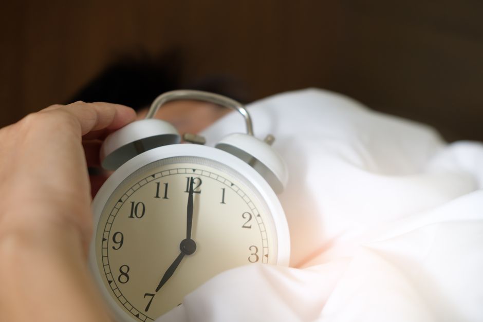 Perte auditive soudaine : comprendre le choc et agir vite A close-up of a hand reaching for a ringing alarm clock, symbolizing waking up in the morning.