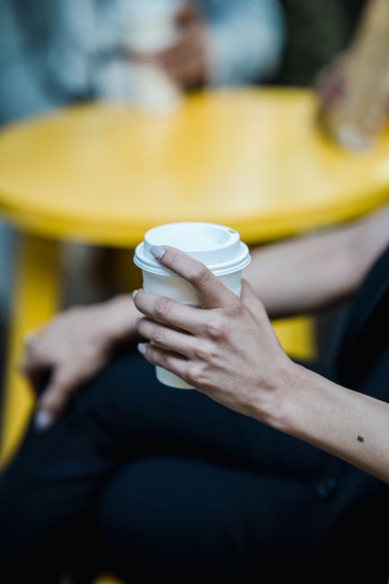 A close-up shot of a hand holding a disposable coffee cup at a cafe. Ideal for lifestyle and coffee break themes.