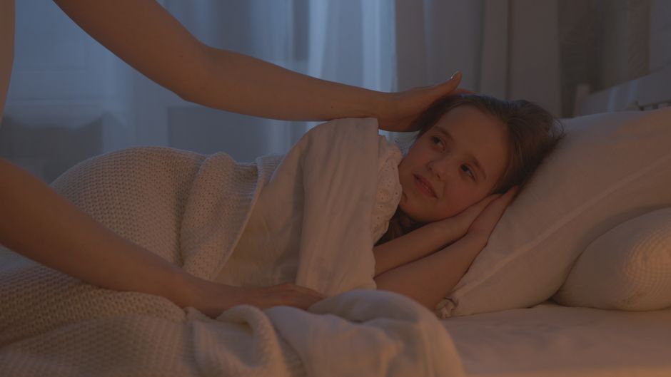 A comforting scene of an adult tucking a child into bed, creating a warm and peaceful bedtime atmosphere.