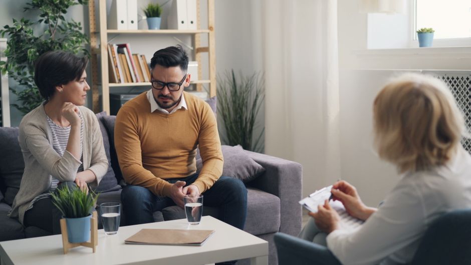 Pourquoi trompe-t-on quand on aime encore? Les causes de l’infidélité A couple engaged in a counseling session with a therapist in a cozy room.