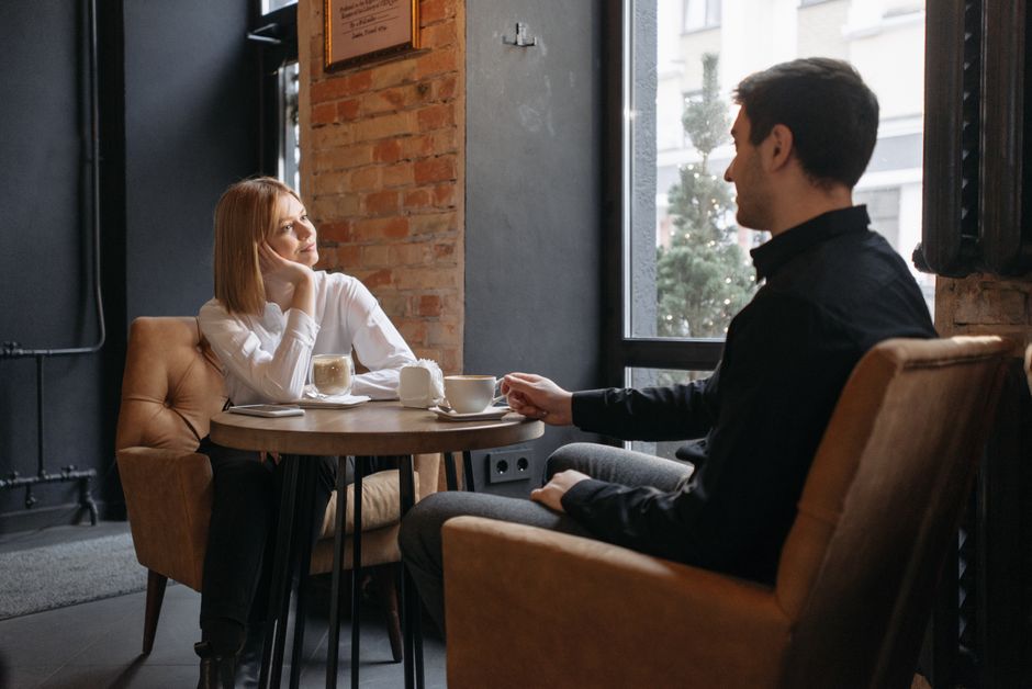 A couple enjoying coffee and conversation in a cozy café setting by the window.