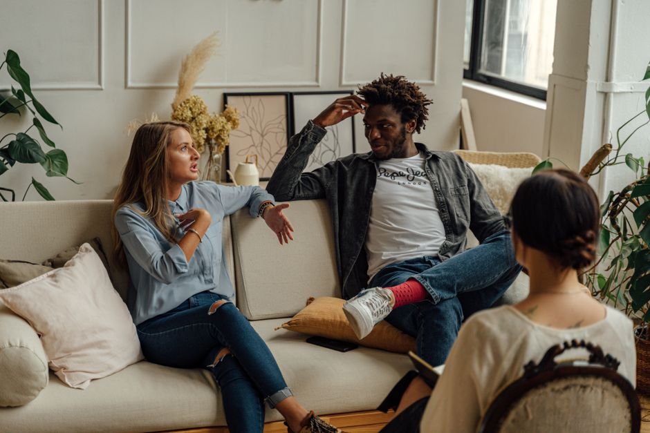 Conseil prénuptial : préparer le mariage sans jouer la comédie A couple is engaged in a lively conversation during a therapy session with a counselor.