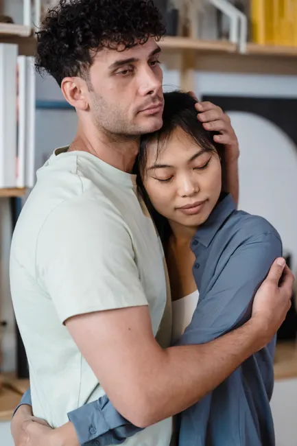A couple shares a tender embrace indoors, showcasing affection and intimacy.