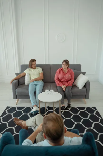 A couple sitting on a sofa during a therapy session with a professional therapist.