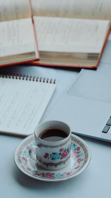 A cup of coffee on a desk with an open laptop and notebooks, ideal for study sessions.