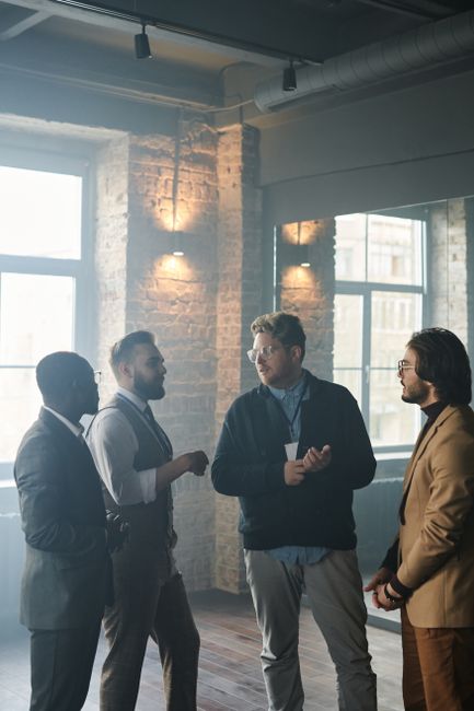 A diverse group of professionals engaging in conversation in a modern indoor setting.
