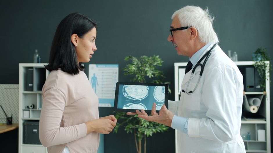 A doctor showing a female patient brain MRI scans in a clinical setting for consultation.