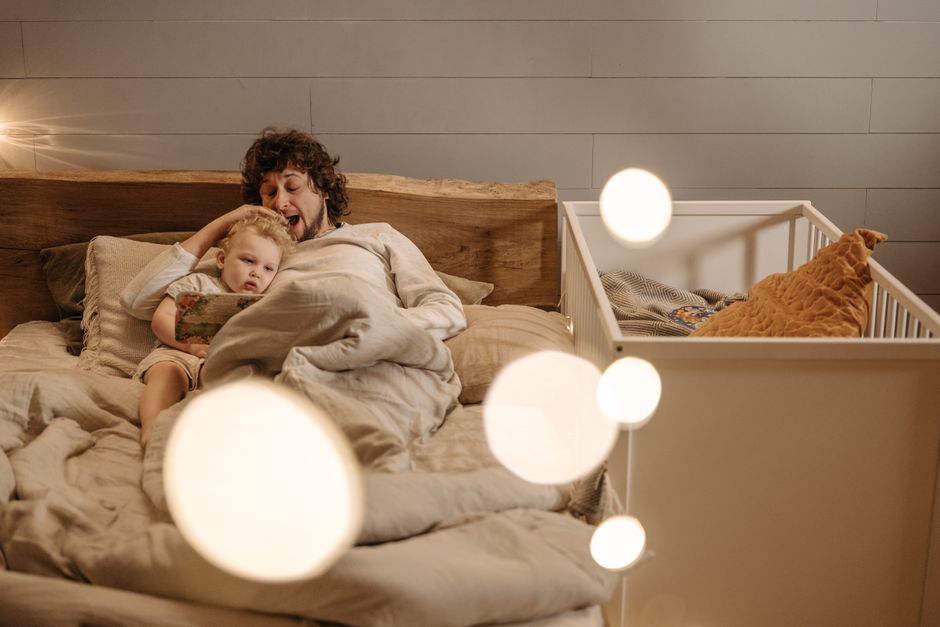 A father and child enjoy a bedtime story together, creating a warm family moment in a cozy indoor setting.
