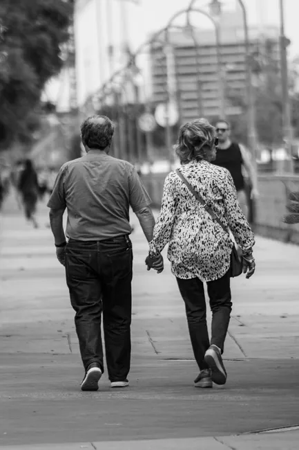 A happy senior couple holding hands on a city street, enjoying a casual stroll.