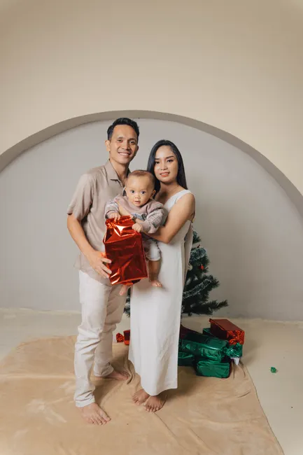 A joyful family portrait with a Christmas tree and gifts, showcasing warmth and holiday spirit.