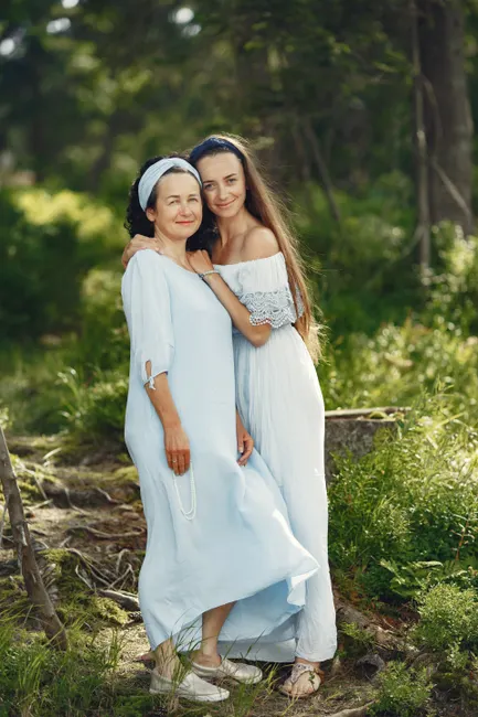 A loving mother and daughter share a tender embrace in a serene outdoor setting.