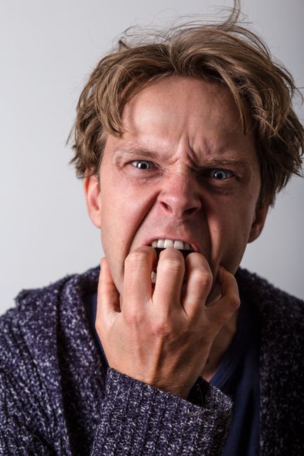 A man displaying intense emotion with fingers near mouth, close-up shot.