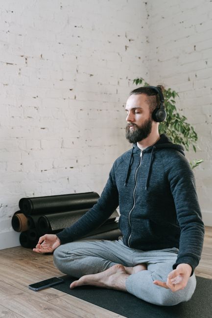 A man meditating indoors with headphones on, promoting relaxation and mental wellness.