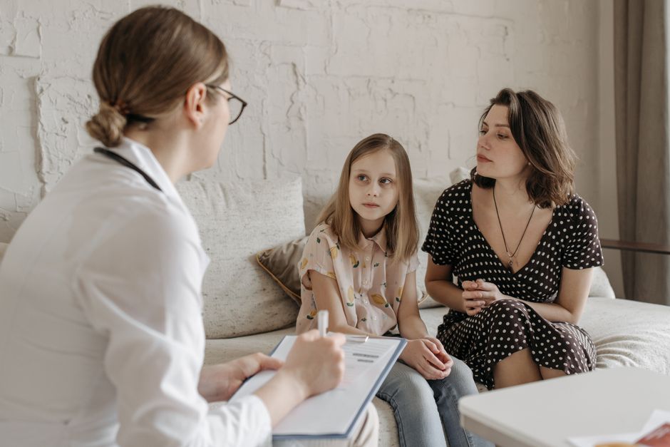 A mother and daughter consult with a doctor during a medical appointment indoors.