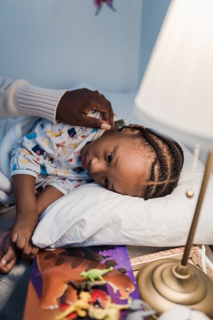 A mother tucking in her young child in a cozy bedroom setting for a peaceful bedtime.