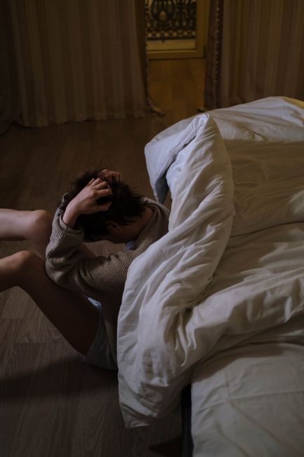A person sitting on the floor with hands on head, expressing stress and anxiety at night.