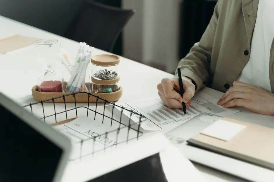 A person writing on a document at a tidy desk with office supplies.