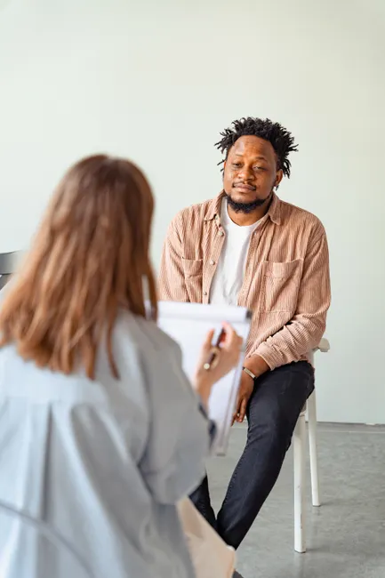 A psychotherapy session between a male patient and a female counselor discussing mental health.