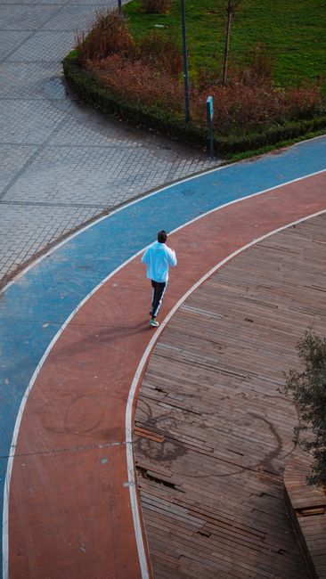 A runner in sportswear jogs on a colorful track, viewed from above. Vibrant and dynamic.