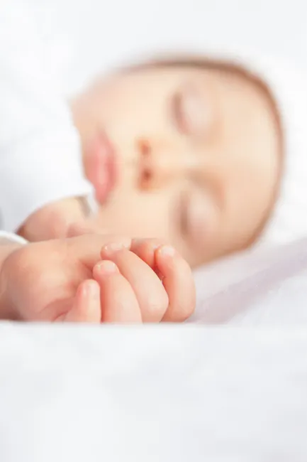 A serene and innocent close-up of a sleeping newborn baby with soft focus.