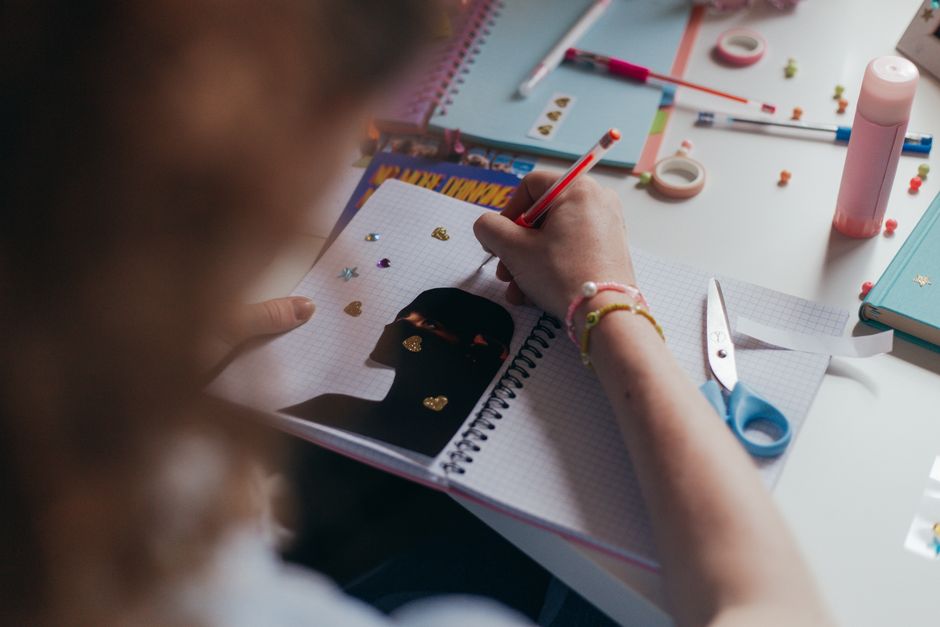Dépression et autisme : repérer ce qui change, aider sans réduire la personne A student decorates a notebook with stickers and colorful supplies, engaging in a creative art project.