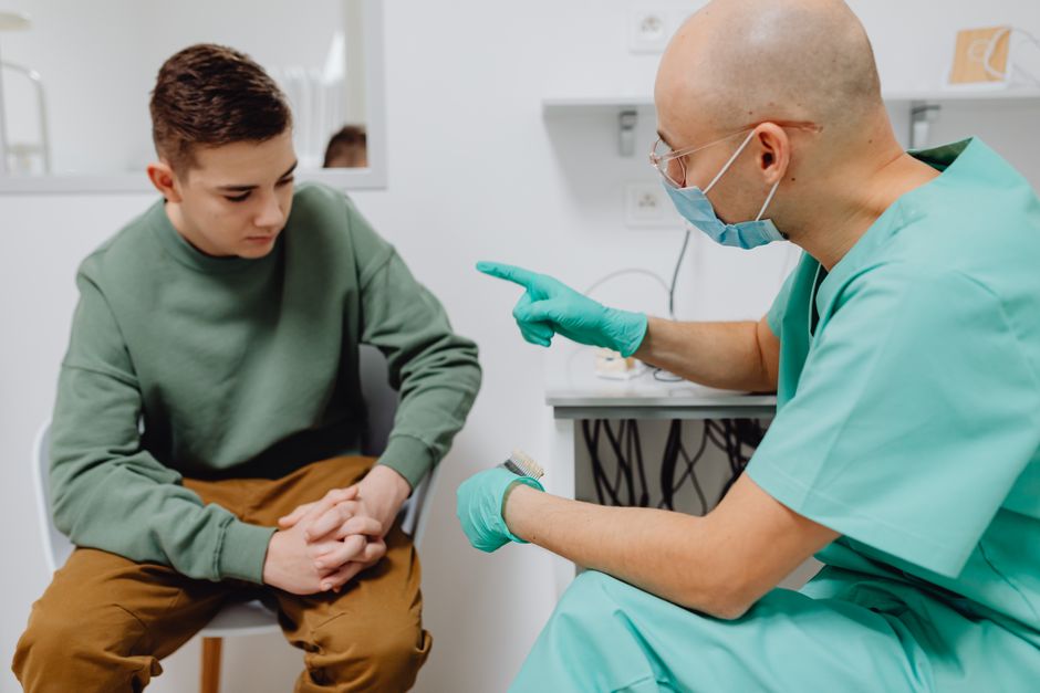 A teenager consults a doctor in a clinic, discussing health concerns.