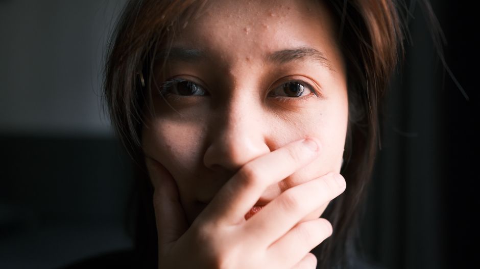 EFT tapping : ce que montrent les études publiées en 2025 et 2026 A thoughtful close-up portrait of a person covering their mouth with a hand, expressing emotion.