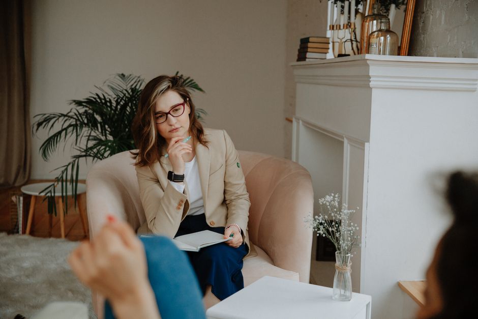 Déterminants sociaux de la santé mentale : pourquoi le self-care ne suffit pas A thoughtful female therapist engages in a counseling session indoors, promoting mental well-being.