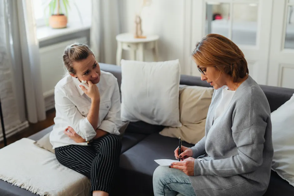 A thoughtful therapy session between two women in a cozy room.