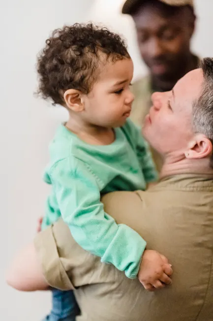 A touching moment of family reunion between a military parent and child indoors.