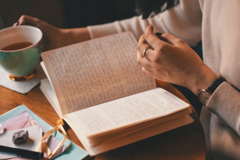 Pensées obsessionnelles et trouble bipolaire : sortir de la boucle sans lutter contre soi A woman writes in a journal while enjoying a cup of coffee at a wooden table.