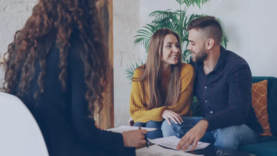 A young couple discussing plans with an advisor in a modern office setting.