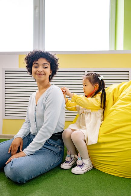 A young girl interacts with her caregiver in a vibrant indoor playroom, fostering bonding and play