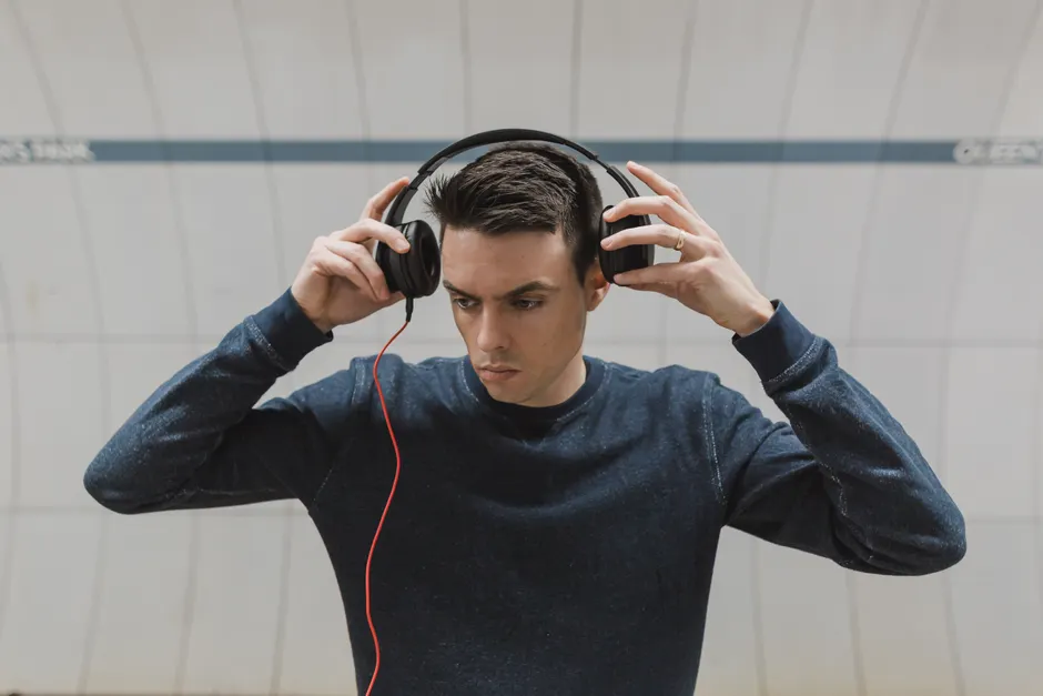 Rêverie compulsive : quand l’imagination devient difficile à interrompre A young man adjusting headphones indoors, focused and fashionably dressed.