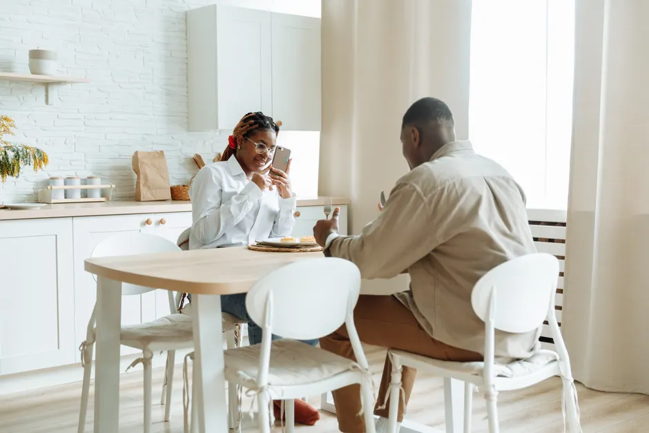 Ma femme me trompe-t-elle? Les signes qui alertent et ceux qui ne prouvent rien African couple enjoying breakfast while capturing moments on phone at a cozy dining table.