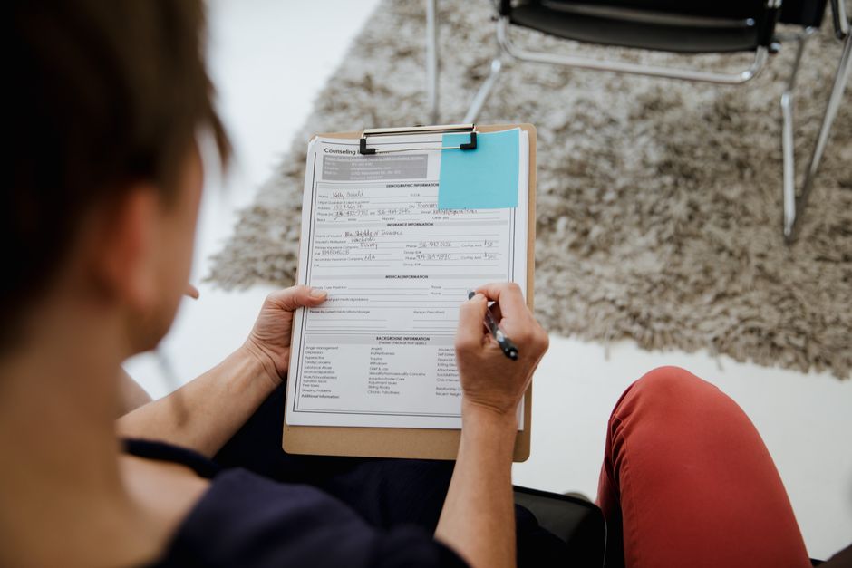 Diagnostic de l’autisme chez l’adulte : ce que l’évaluation mesure vraiment An adult woman writing on a counseling form during a business appointment in an office setting.