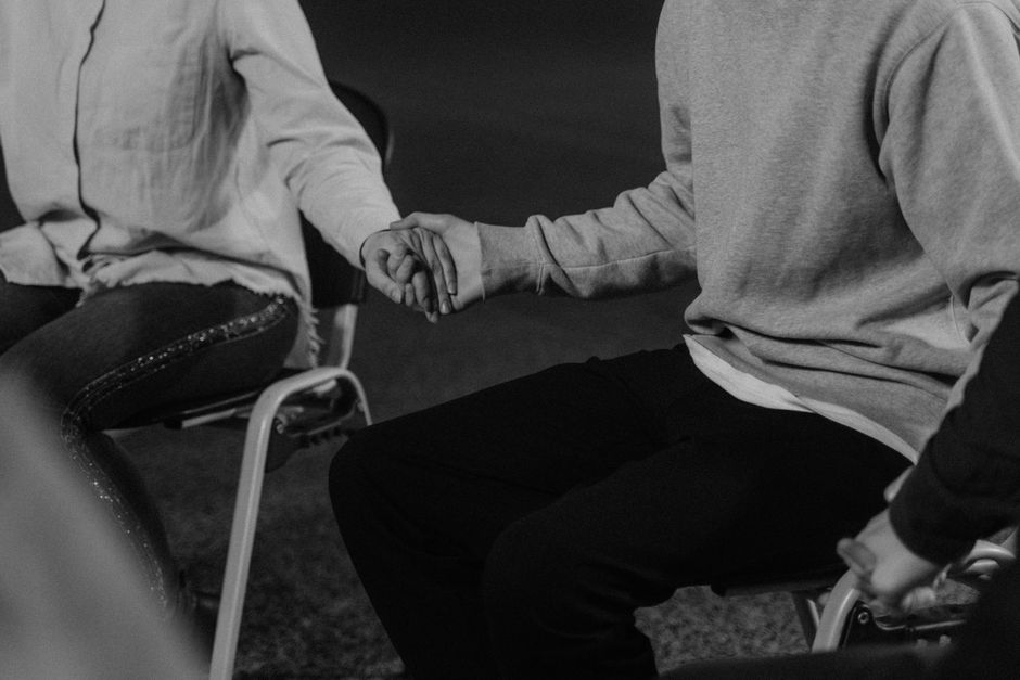Black and white image of people holding hands in a group therapy session enhancing mutual support.